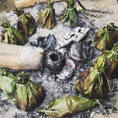 Ở vùng núi cao nguyên Hà Giang, nơi khí hậu ẩm ướt và thiên nhiên ưu đãi, rong rêu mọc lên tươi tốt quanh năm. Tận dụng món quà từ đất trời cùng sự sáng tạo trong văn hóa ẩm thực, người dân nơi đây đã biến rêu thành một đặc sản độc đáo – rêu nướng. Không chỉ là món ăn yêu thích của người bản địa, rêu nướng Hà Giang còn nổi tiếng gần xa, trở thành “cực phẩm” mà du khách nào cũng muốn thử khi ghé thăm Hà Giang.Rêu nướng Hà Giang, món ăn đặc trưng của dân tộc Tày, không chỉ ngon mà còn mang lại nhiều lợi ích sức khỏe: lưu thông khí huyết, giải nhiệt, ổn định huyết áp và tăng cường sức đề kháng. Theo kinh nghiệm truyền đời của người Tày, muốn có rêu ngon, phải chọn những bãi rêu lớn – nơi rêu vừa nhiều, vừa tươi non. Rêu tươi sau khi hái về được vò đập kỹ để loại bỏ nhớt và phù sa. Khi vớt rêu, người ta thường đứng dưới suối, dùng tay quơ ngang dòng nước chảy để chọn những ngọn rêu non nhất. Điều thú vị là rêu chỉ “sống” trong 7 ngày: mọc lên 3-4 ngày là thời điểm lý tưởng để thu hoạch, nếu để quá lâu, rêu chuyển màu trắng bệnh, không còn ăn được.
Rêu nướng là món ăn theo mùa, phụ thuộc vào những bãi rêu lớn, nên không phải lúc nào bạn cũng dễ dàng thưởng thức. Rêu sau khi rửa sạch sẽ được trộn cùng sả, gừng, muối, hạt tiêu, rồi gói trong lá dong và nướng trên bếp lửa, tỏa hương thơm ngát. Ngoài nướng, rêu còn có thể nấu với nước xương hầm hay nước luộc gà. Nhiều gia đình ở Hà Giang thậm chí phơi khô rêu, treo trên gác bếp để bảo quản, sẵn sàng mang ra đãi khách quý. Nếu có cơ hội lên vùng cao và được nếm thử món rêu đặc biệt này, bạn quả là may mắn!
Rêu nướng